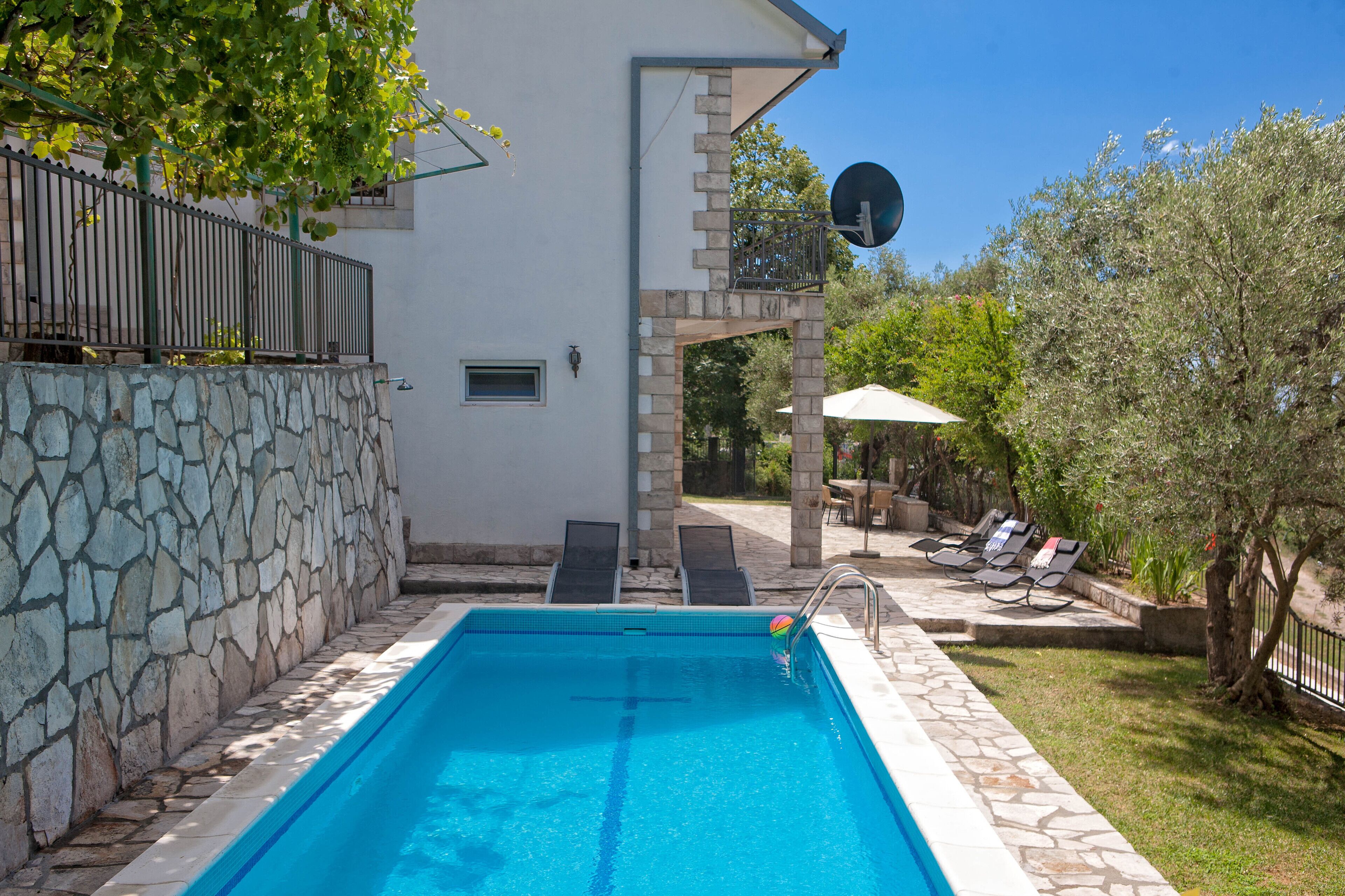 Una piscina con lettini e una parete in pietra.