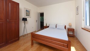 Ein Schlafzimmer mit einem hölzernen Bett, einem Nachttisch, einer Stehlampe, einem Kleiderschrank und einem Bild an der Wand.