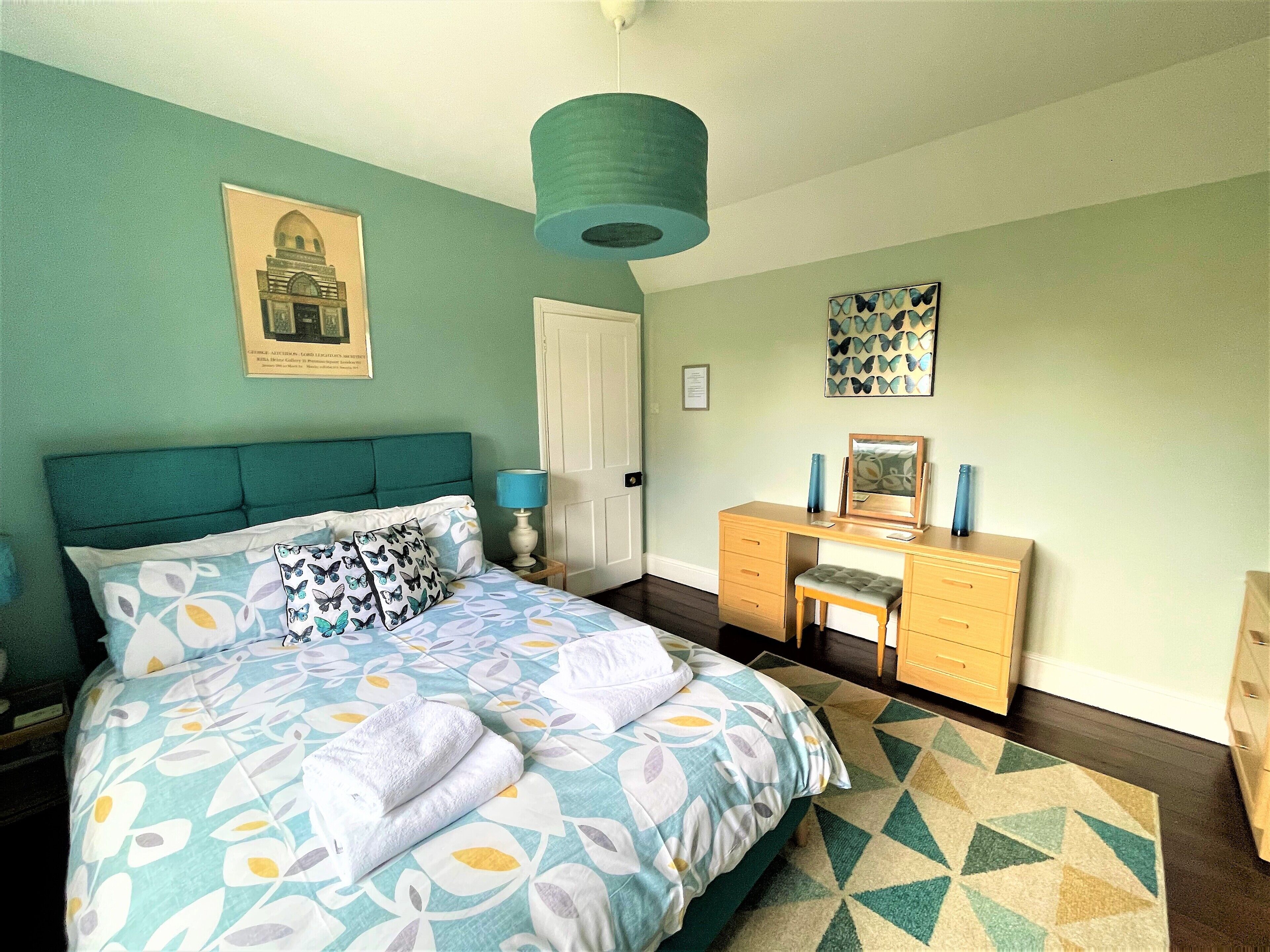 Une chambre à coucher comprenant un lit, un bureau, une chaise, une lampe et un tapis à motifs.
