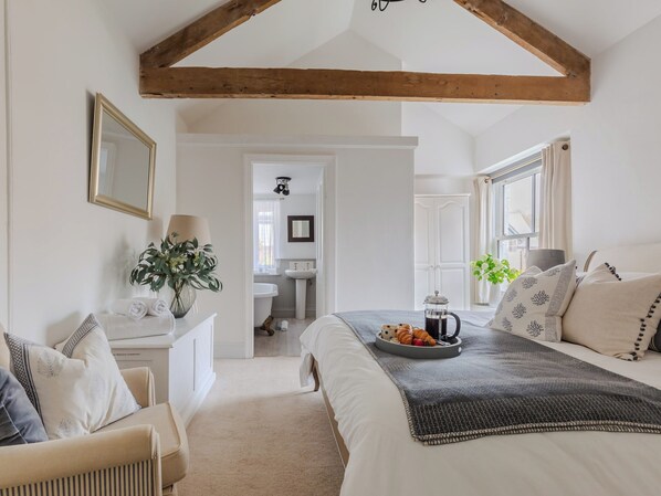 Une chambre à coucher avec un lit, une table de chevet avec une lampe, une fenêtre avec des rideaux et une vue sur la salle de bain.