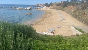 A beach with clear blue water, a sandy shore, and a row of white inflatable loungers. - Villa Manzanillo w/ Private Pool, Sea Views, Double Badminton Court (pickleball) (Peyia)