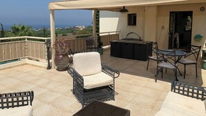 A covered outdoor patio with a table and chairs, a sofa, and a potted plant. - Villa Manzanillo w/ Private Pool, Sea Views, Double Badminton Court (pickleball) (Peyia)