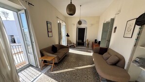 A living room with a patterned floor, a sofa, a coffee table, and a view through a glass door. - Elegant Apartment in Vejer Old Town, renovated but with lovely original features (Vejer de la Frontera)
