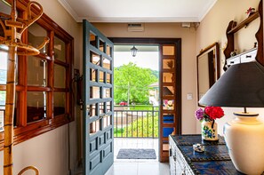 A hallway with a wooden door leading to a balcony with a view of a tree and a red car. - Ideal house for families. Private heated swimming pool. (Cangas de Onís)