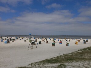 A beach with numerous colorful beach huts and a large blue sign with a compass. - Comfortable vacation home / close to the beach / quiet location - directly behind the dike (Dornumersiel)