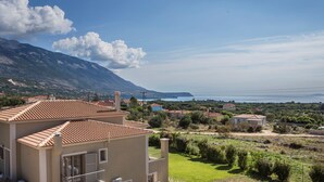 A residential building with a tiled roof, a balcony, and a view of a coastal landscape with mountains and a body of water. - Sailing Villa Kefalonia (Karavados / Leivathos)
