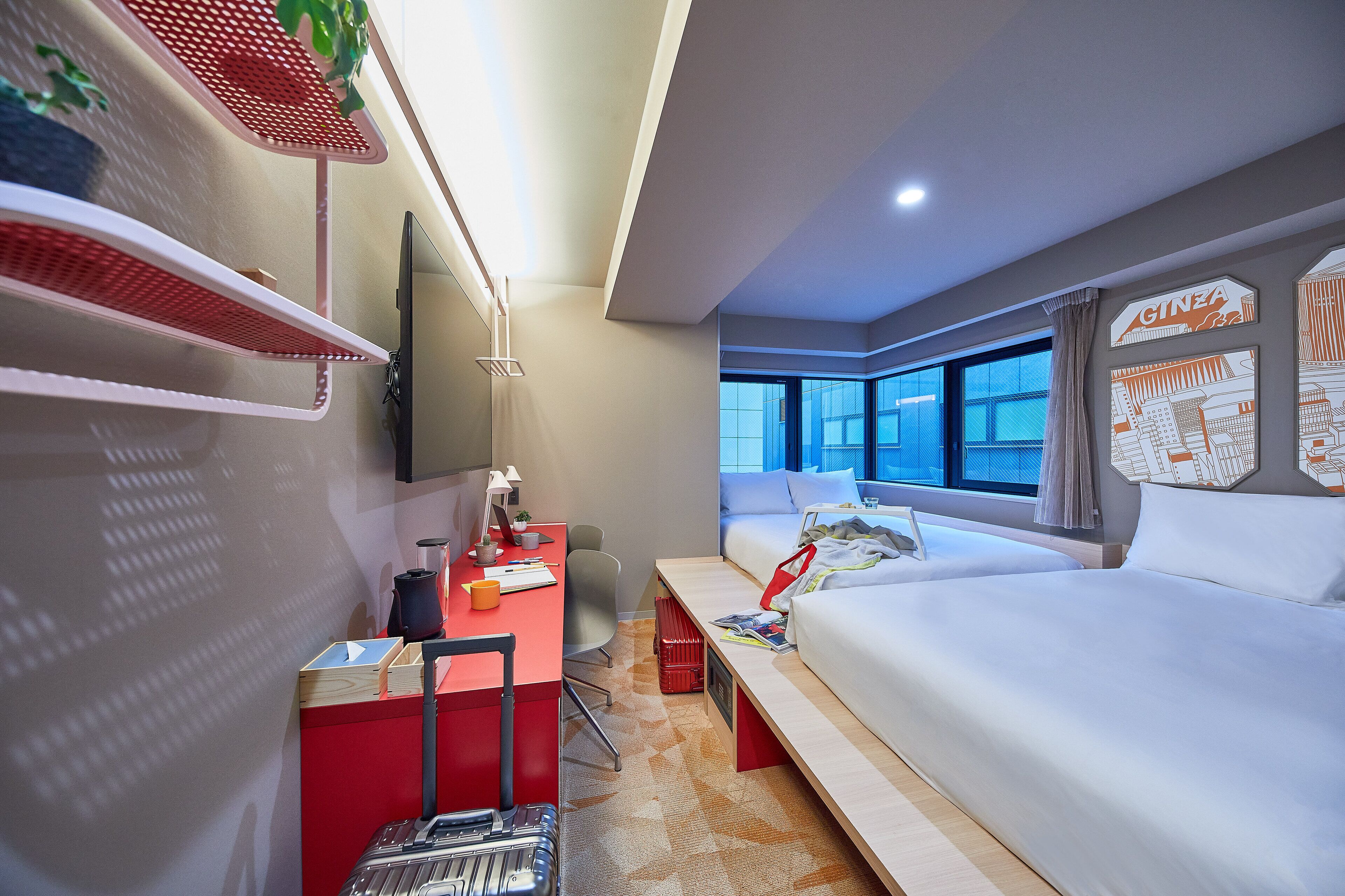 Een hotelkamer met een bed, bureau, stoel en planken.