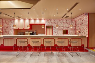 Un área de bar moderna con una barra larga, varios taburetes e iluminación colgante.