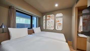 Une chambre d’hôtel avec un grand lit, une fenêtre avec des rideaux, un mur décoré d’une œuvre d’art représentant un paysage urbain et une armoire.