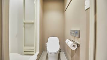 A small, clean bathroom with a toilet, a paper towel dispenser, and a wall-mounted control panel.