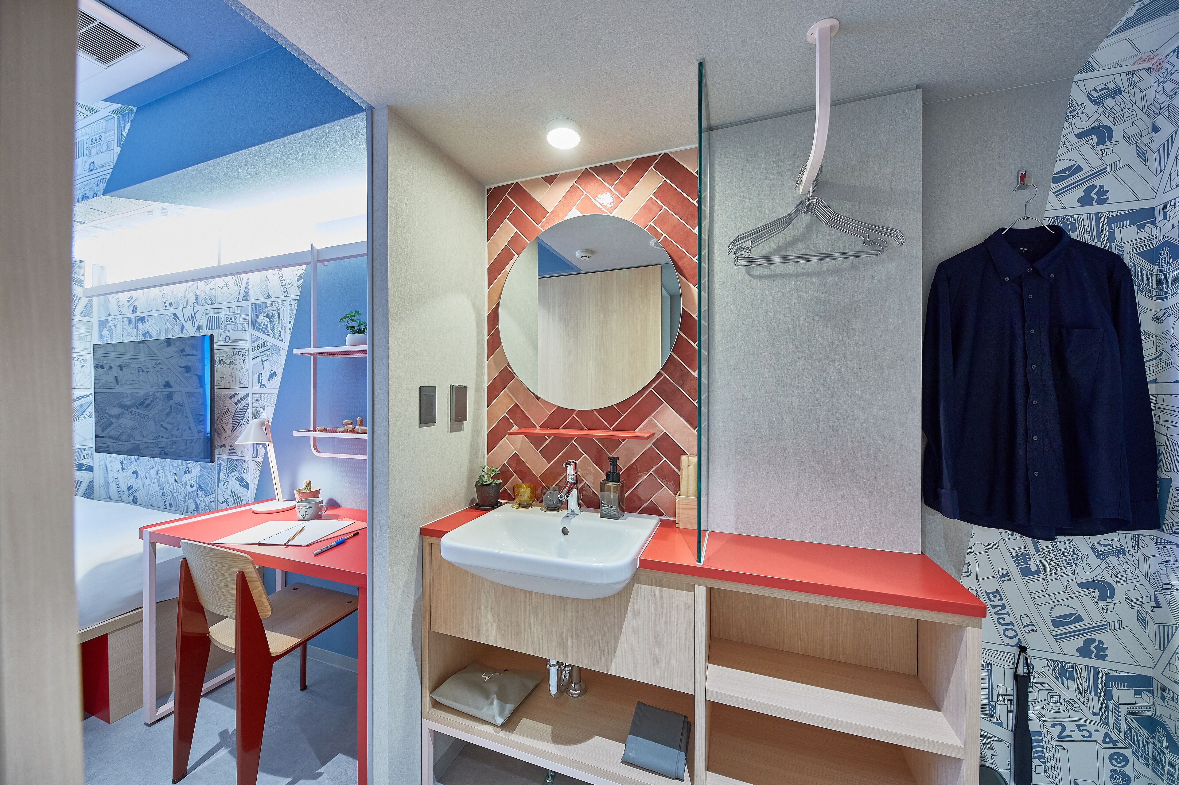 A modern bathroom with a red countertop, a white sink, and a mirror with a geometric backsplash.