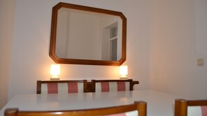 Una mesa de comedor con cuatro sillas, un espejo grande encima y dos lámparas fijadas a la pared.
