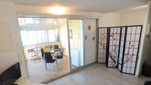 A modern living room with a dining area, a large mirror, and a sliding door leading to an adjacent room. - Facing the sea, sandy beach, everything nearby (LA SEYNE SUR MER)