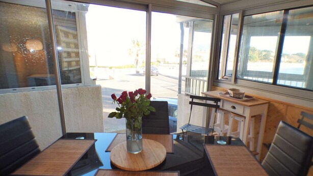 A dining area with a table and chairs, a vase with flowers, and a view of the outside. - Facing the sea, sandy beach, everything nearby (LA SEYNE SUR MER)
