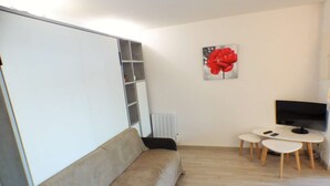 A modern living room with a sofa, a TV, and a small table with chairs. - Facing the sea, sandy beach, everything nearby (LA SEYNE SUR MER)