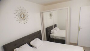 A bedroom with a bed, a mirror, and a wall clock. - Facing the sea, sandy beach, everything nearby (LA SEYNE SUR MER)