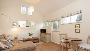 A living room with a sofa, a TV, a dining table, and chairs.