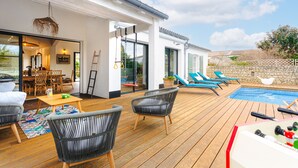 A spacious outdoor deck with a pool, lounge chairs, and a foosball table.