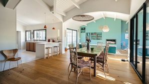 A spacious kitchen with wooden flooring, a dining area with a glass table, and a view of the outdoors.