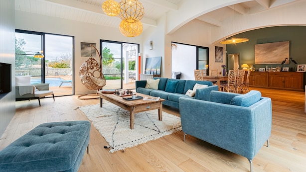 A spacious living room with a blue sofa, a wooden coffee table, and a hanging light fixture.