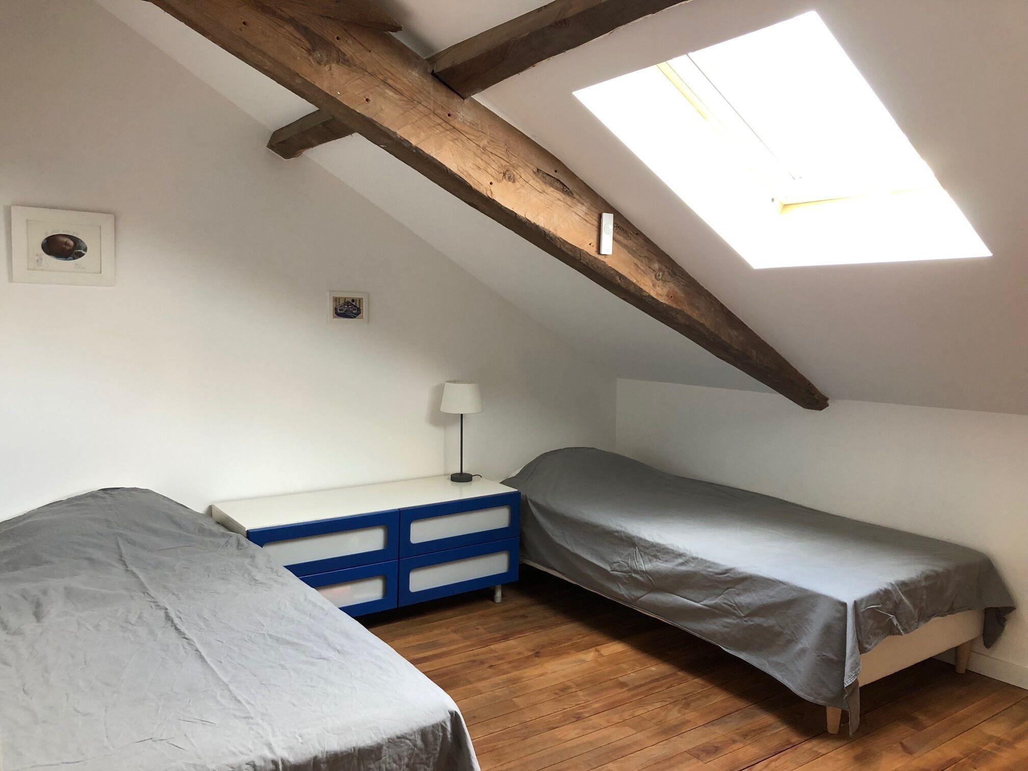 Ein kleines Schlafzimmer im Dachgeschoss mit zwei Einzelbetten, einem Schreibtisch und einem Dachfenster.