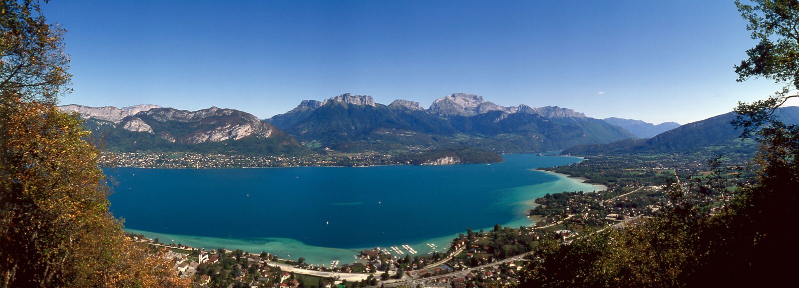 Vista panorámica de un pueblo costero con un lago extenso, rodeado de montañas.