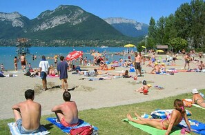 Enjoy the beach with umbrellas and sun loungers, surrounded by lush greenery and mountains.