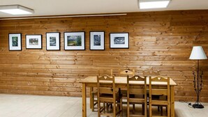 A wooden-paneled room with a dining table and chairs, a floor lamp, and five framed pictures on the wall. - Résidence le Bois de la reine - 2-room apartment cabin for 4/6 people (Besse-Et-Saint-Anastaise)