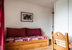 Ein Schlafsofa aus Holz mit einer Stegdecke, ein Holzstuhl und ein gerahmtes Bild an der Wand.