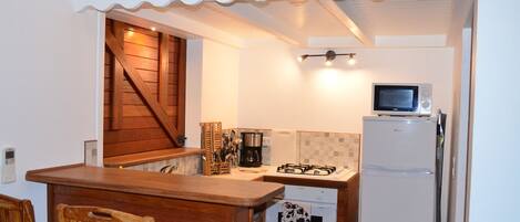 A compact kitchen with a wooden table, a built-in stove, a microwave, and a refrigerator.