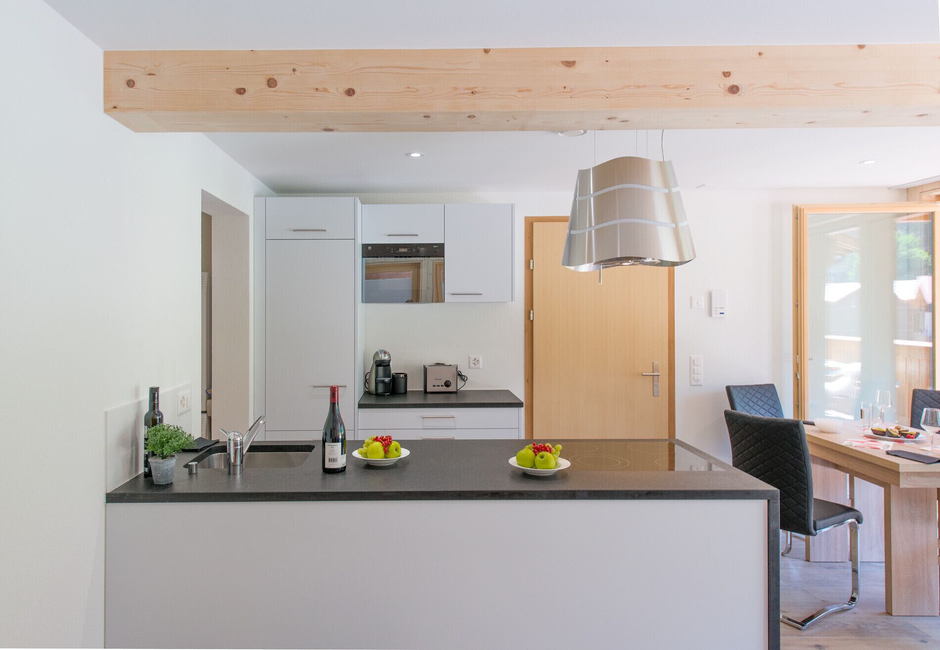 Une cuisine moderne avec un îlot central, des armoires blanches et un plafond en bois.