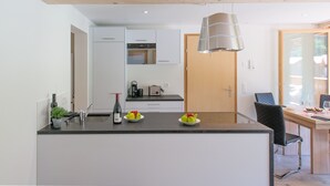 A modern kitchen with a central island, white cabinets, and a wooden ceiling. - Chalet Belmont 7 - top location (Wengen)