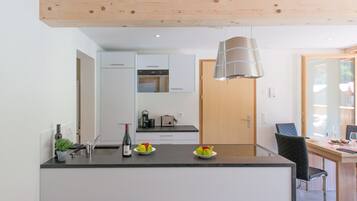 Une cuisine moderne avec un îlot central, des armoires blanches et un plafond en bois.