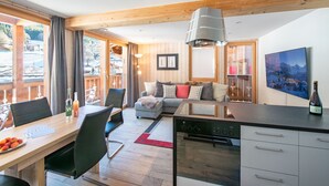 A modern kitchen with a dining area, wooden beams, a sofa, and a large window overlooking a snowy landscape. - Chalet Belmont 7 - top location (Wengen)