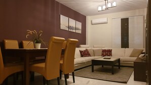 Ein modernes Wohnzimmer mit Essbereich, ausgestattet mit einer Couch, einem Couchtisch und Sesseln.