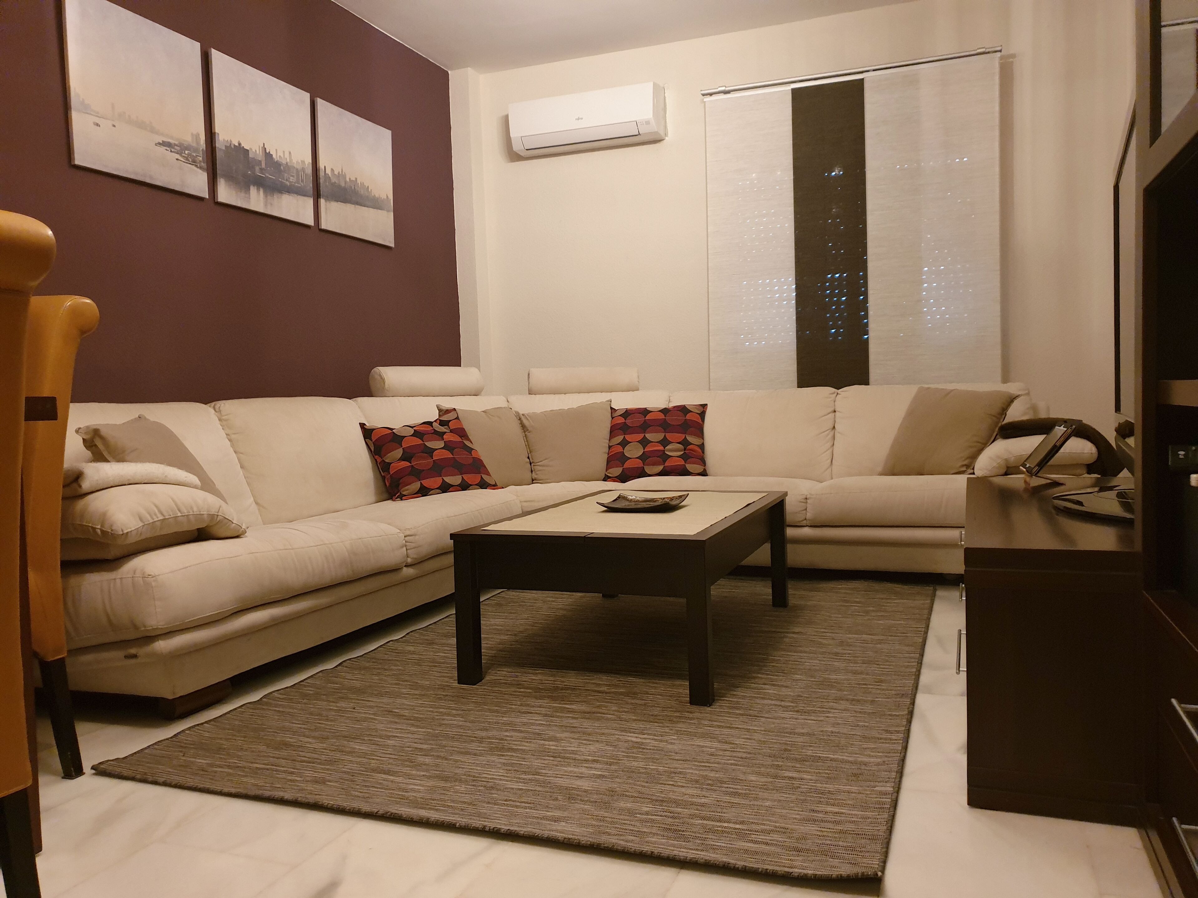 Una sala de estar con un sofá color beige, almohadones estampados, una mesita de centro y una alfombra.