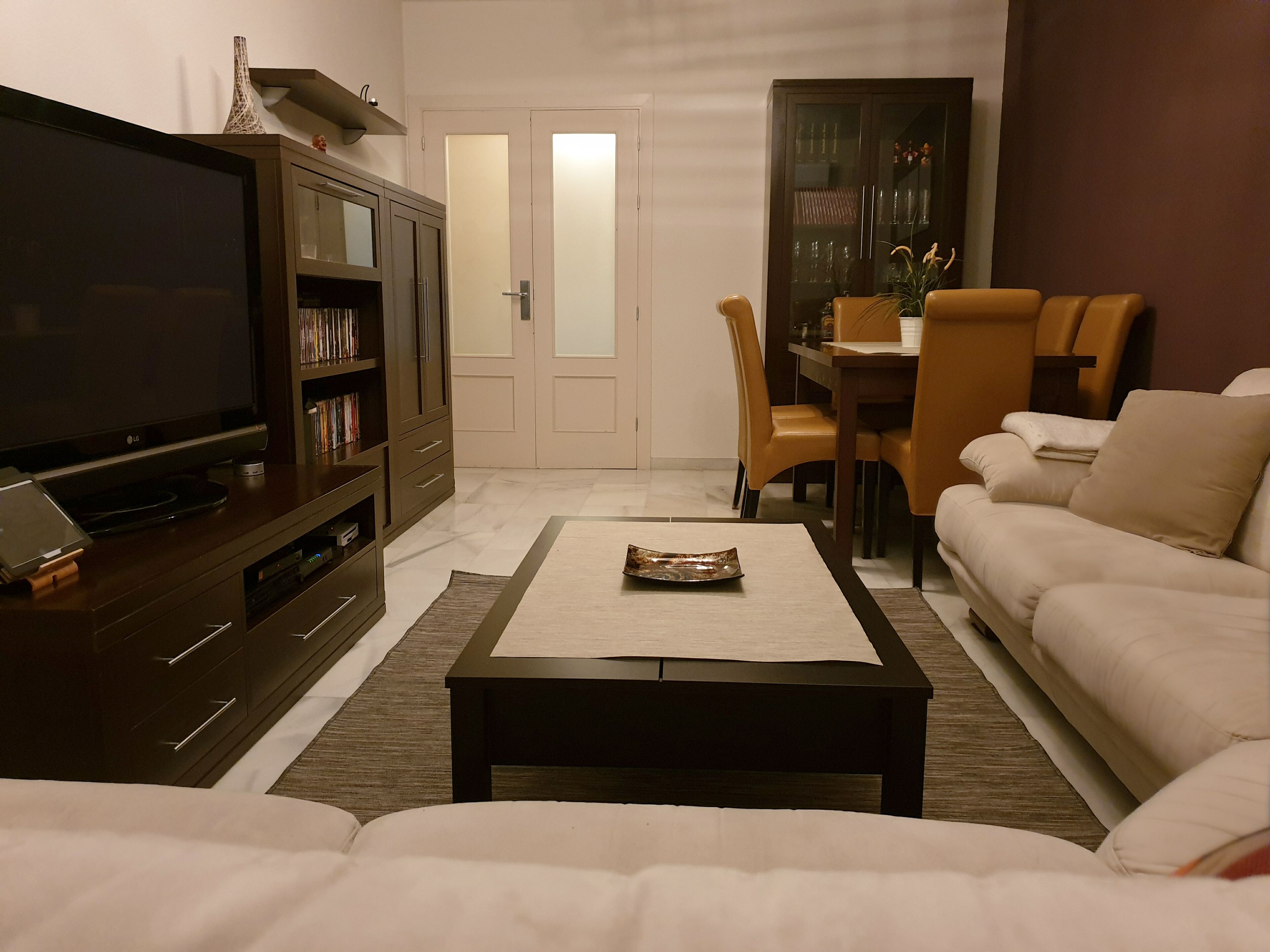 A living room with a TV, bookshelf, sofa, coffee table, and dining area.