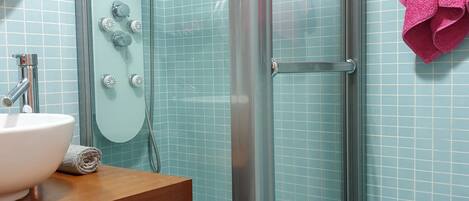 Un baño con ducha de vidrio, lavamanos y espejo.