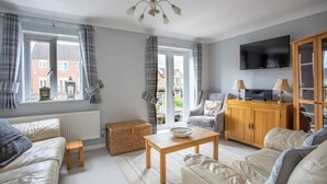 A living room with a sofa, a wooden table, a television, and a cabinet. - Delightful house in Stone, Staffordshire  close to lovely canal side walks.   (Stone)