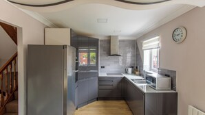 A modern kitchen with grey cabinets, a stainless steel refrigerator, a microwave, and a window with blinds. - Delightful house in Stone, Staffordshire  close to lovely canal side walks.   (Stone)