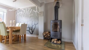 A cozy room with a wood-burning stove, a dining table with chairs, and a wall mural. - Delightful house in Stone, Staffordshire  close to lovely canal side walks.   (Stone)