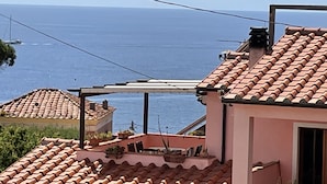 Un bâtiment situé sur la côte, doté d’un toit en tuiles, d’une pergola et offrant une vue sur la mer.
