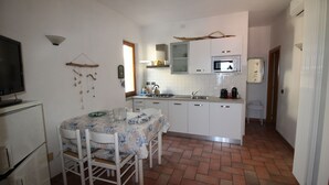 Une cuisine compacte avec des meubles blancs, un four à micro-ondes et un coin repas comprenant une table et des chaises.