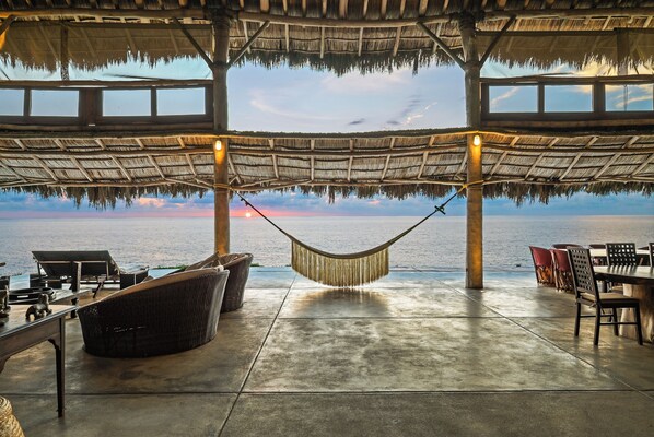 Un espacio de relax junto a la playa con una hamaca, asientos y vistas al océano.