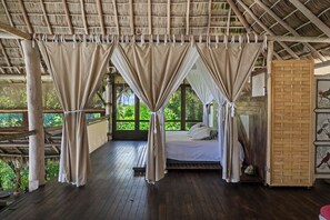Una habitación con cama, cortinas y vistas al verdor.