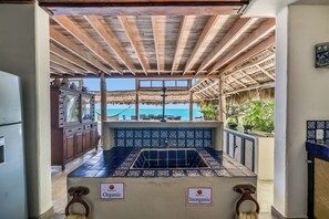 Un área de cocina con vista al mar, que cuenta con un salpicadero de azulejos y armarios de madera.