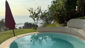 A swimming pool with a view of the ocean and surrounding greenery.