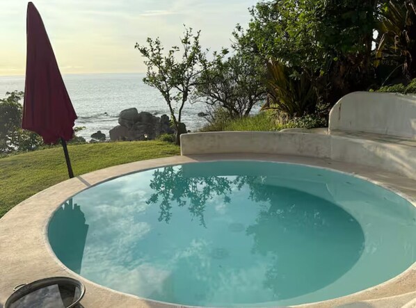 En swimmingpool med utsikt över havet och den omgivande vegetationen.