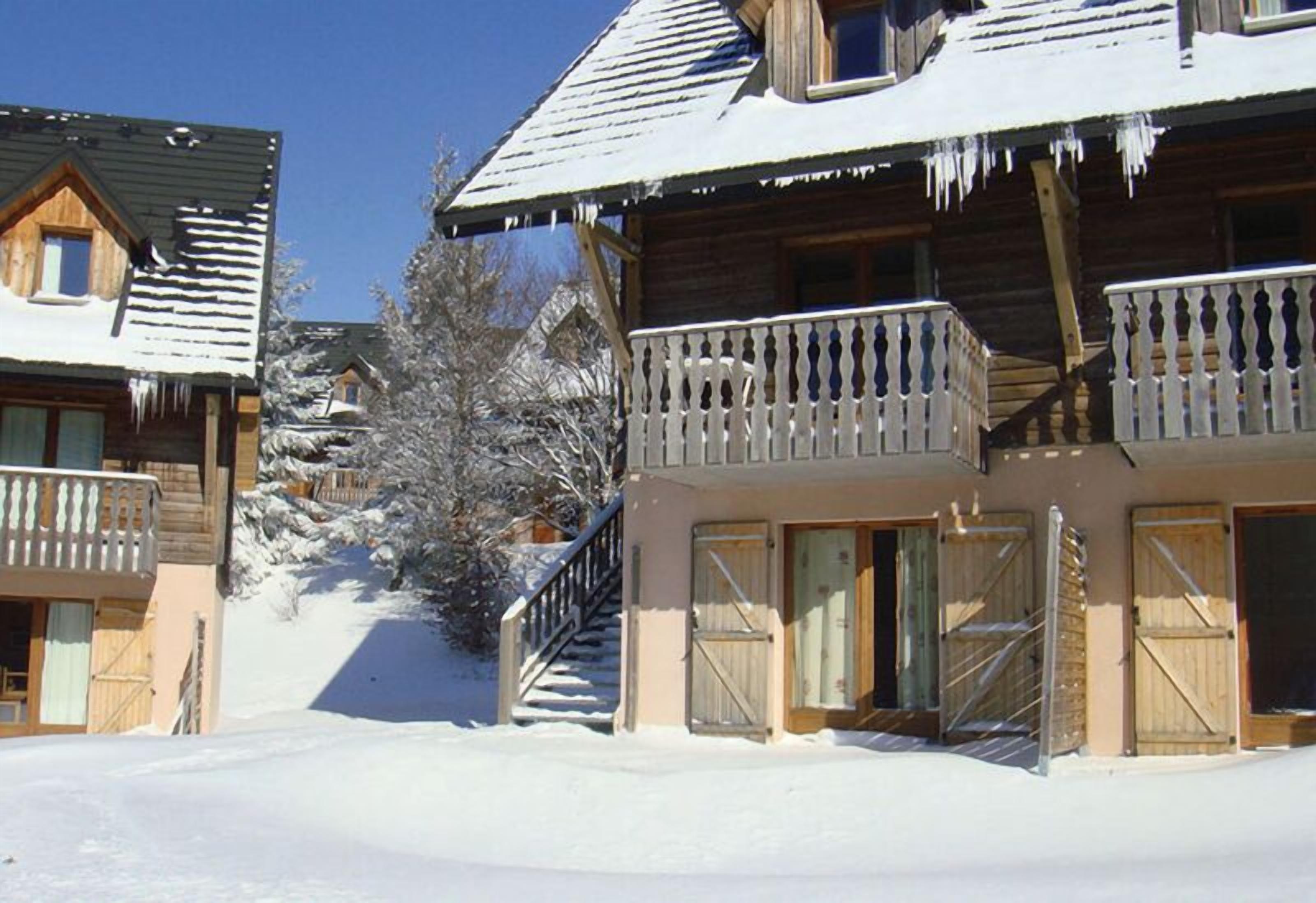 Une cabane en bois dotée d’un balcon, entourée de neige.