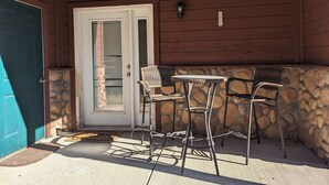 A covered patio with a stone wall, a white door, and two wicker chairs with a small table. - Summer Sale: Mountain Retreat in Grand Lake (Grand Lake)